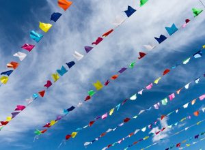 small-cute-colorful-flags-rope-hanging-outside-holiday-with-bright-blue-sky-white-clouds-background-italy-sardinia
