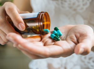 woman-s-hand-pours-medicine-pills-out-bottle
